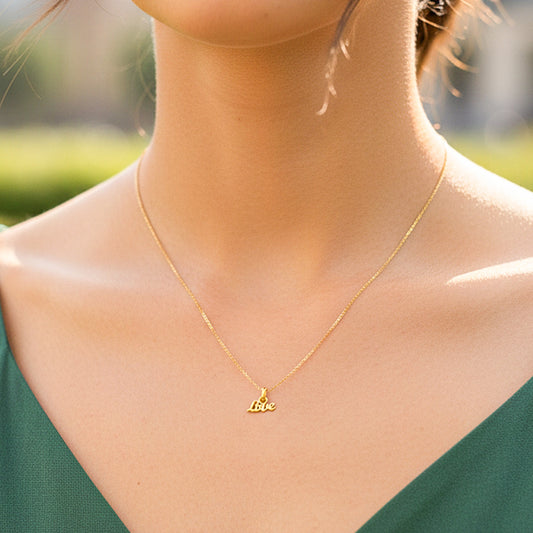 Cuello de modelo usando una cadena con un dije en forma de palabra love mini en oro amarillo de 18 quilates de Joyería Caracas.
