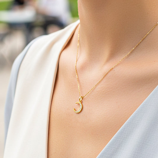 Cuello de modelo usando una cadena con un dije en forma de luna en oro amarillo de 18 quilates con cristales de Joyería Caracas.