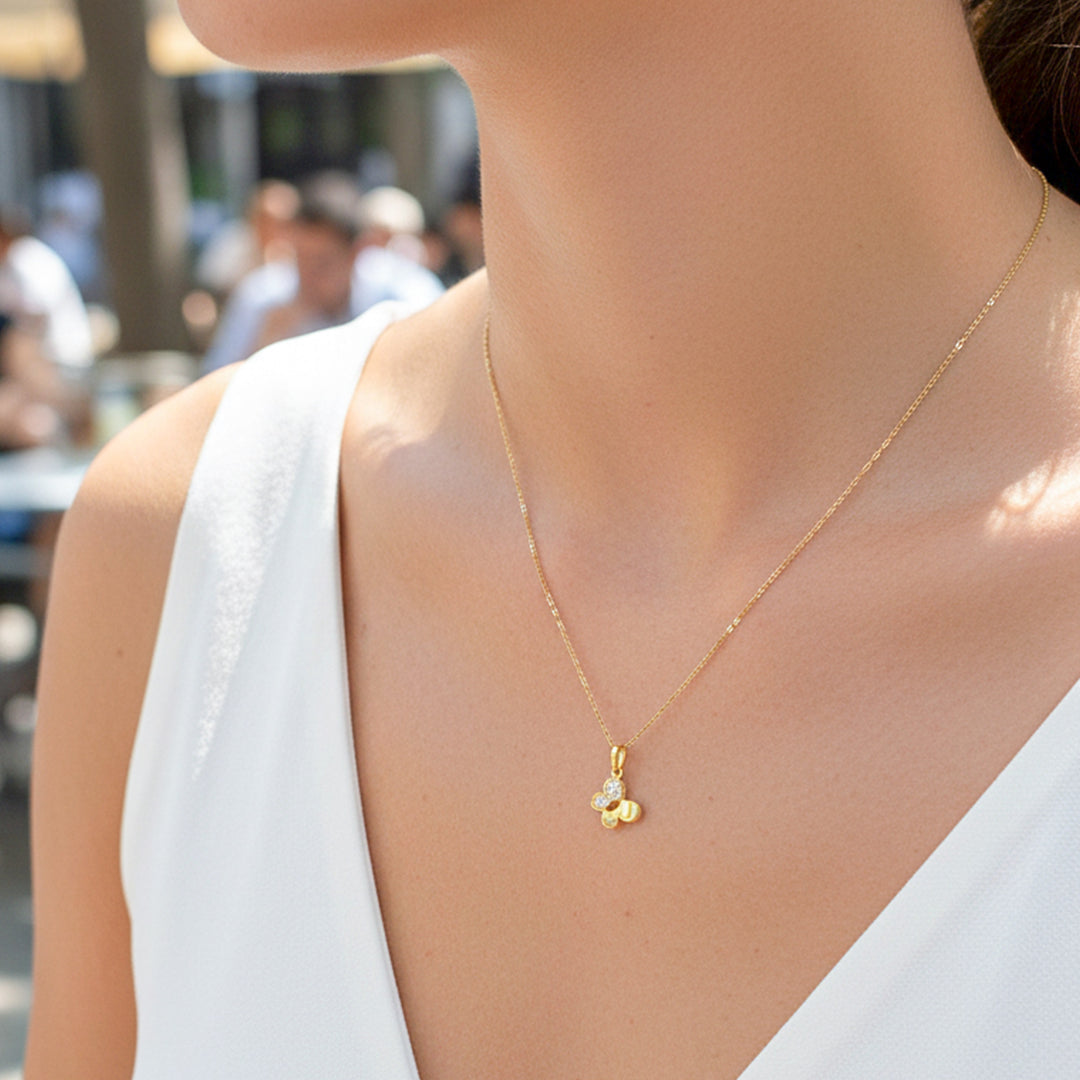 Cuello de modelo usando una cadena con un dije en forma de mariposa en oro amarillo de 18 quilates y cristales de Joyería Caracas.