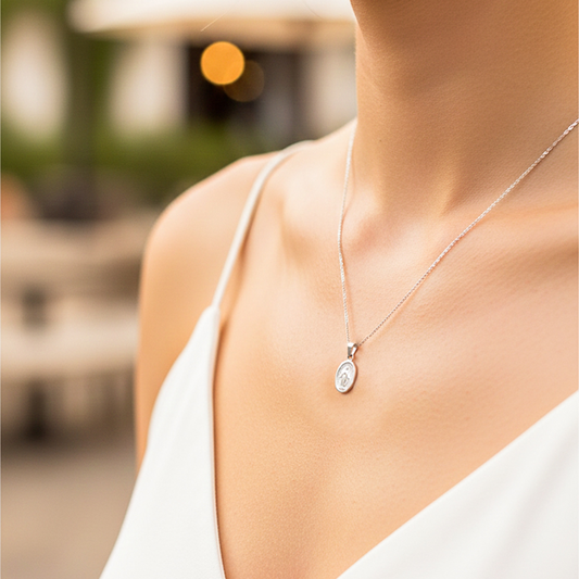 Cuello de modelo usando una cadena con un dije en forma de la Virgen Milagrosa en oro blanco de 18 quilates de Joyería Caracas.