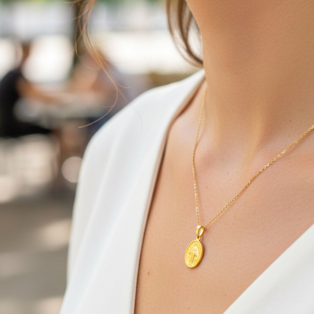 Cuello de modelo usando una cadena con un dije en forma de la Virgen Milagrosa en oro amarillo de 18 quilates de Joyería Caracas.