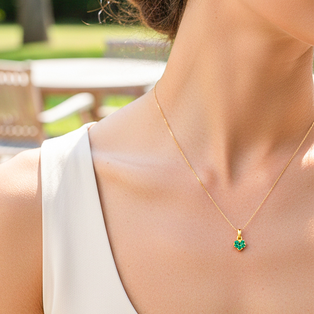 Cuello de modelo usando una cadena con un dije en forma de corazón en oro amarillo de 18 quilates con cristales verdes de Joyería Caracas.