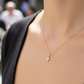 Cuello de modelo usando una cadena con un dije en forma de mini cruz en oro amarillo de 18 quilates con cristales de Joyería Caracas.