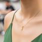 Cuello de modelo usando una cadena con un dije en forma de mini cruz egipcia en oro amarillo de 18 quilates de Joyería Caracas.