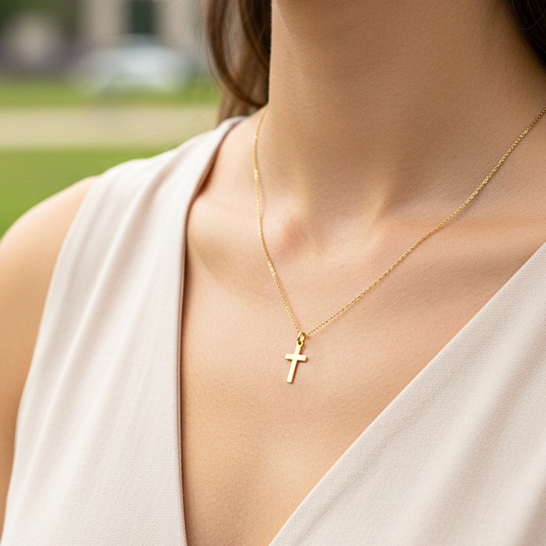 Cuello de modelo usando una cadena con un dije en forma de cruz plana en oro amarillo de 18 quilates de Joyería Caracas.