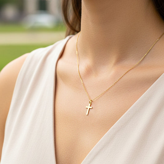 Cuello de modelo usando una cadena con un dije en forma de cruz plana en oro amarillo de 18 quilates de Joyería Caracas.