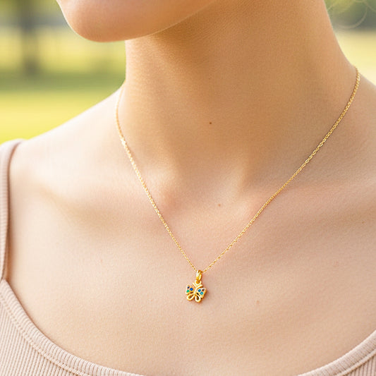 Cuello de modelo usando una cadena con un dije en forma de mariposa en oro amarillo de 18 quilates con cristales multicolor de Joyería Caracas.