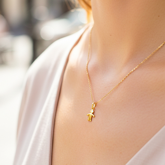 Cuello de modelo usando una cadena con un dije en forma de niño en oro amarillo de 18 quilates de Joyería Caracas.