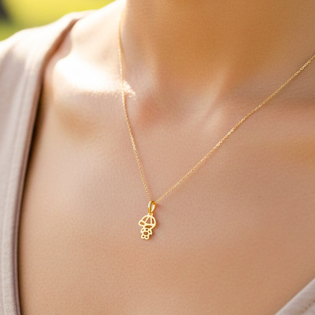 Cuello de modelo usando una cadena con un dije de la silueta de un niño en oro amarillo de 18 quilates de Joyería Caracas.