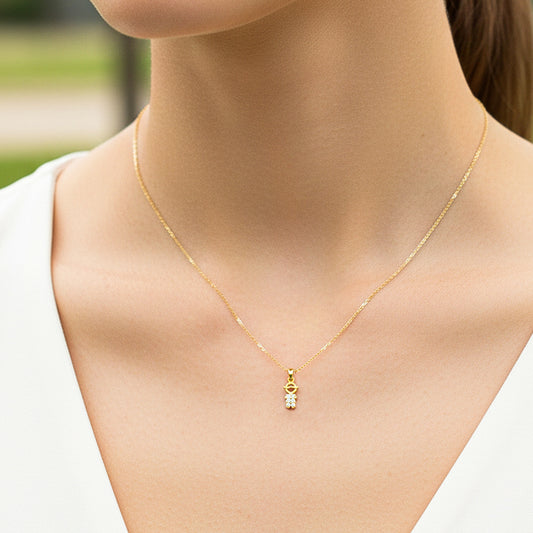 Cuello de modelo usando una cadena con un dije en forma de niño en oro amarillo de 18 quilates con cristales de Joyería Caracas.