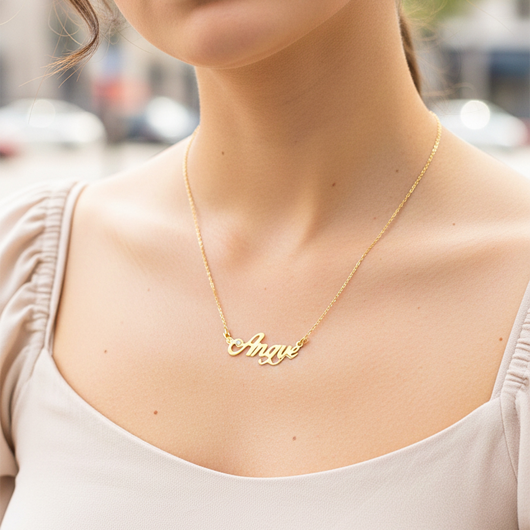Cuello de modelo usando una cadena con un dije de nombre personalizado en oro amarillo de 18 quilates con cristales de Joyería Caracas.
