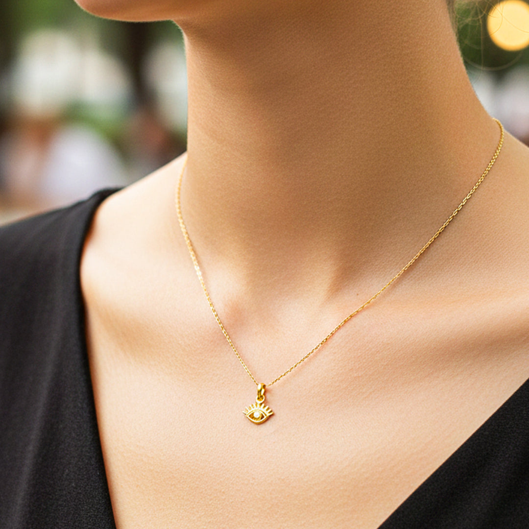 Cuello de modelo usando una cadena con un dije en forma de ojo turco en oro amarillo de 18 quilates de Joyería Caracas.