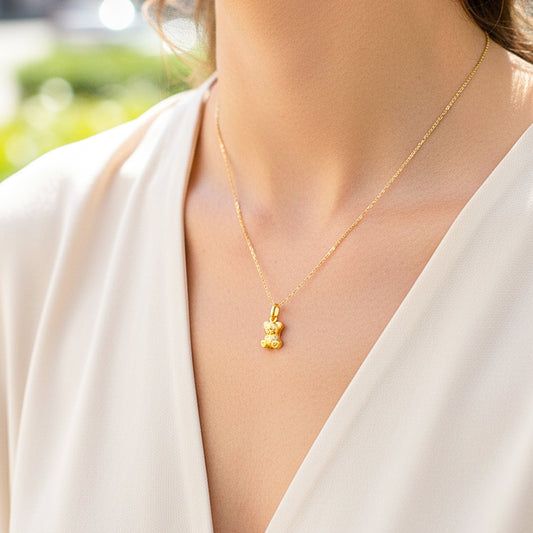 Cuello de modelo usando una cadena con un dije en forma de osito en oro amarillo de 18 quilates de Joyería Caracas.