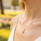 Cuello de modelo usando una cadena con un dije en forma de papá en oro amarillo de 18 quilates con cristales azules de Joyería Caracas.