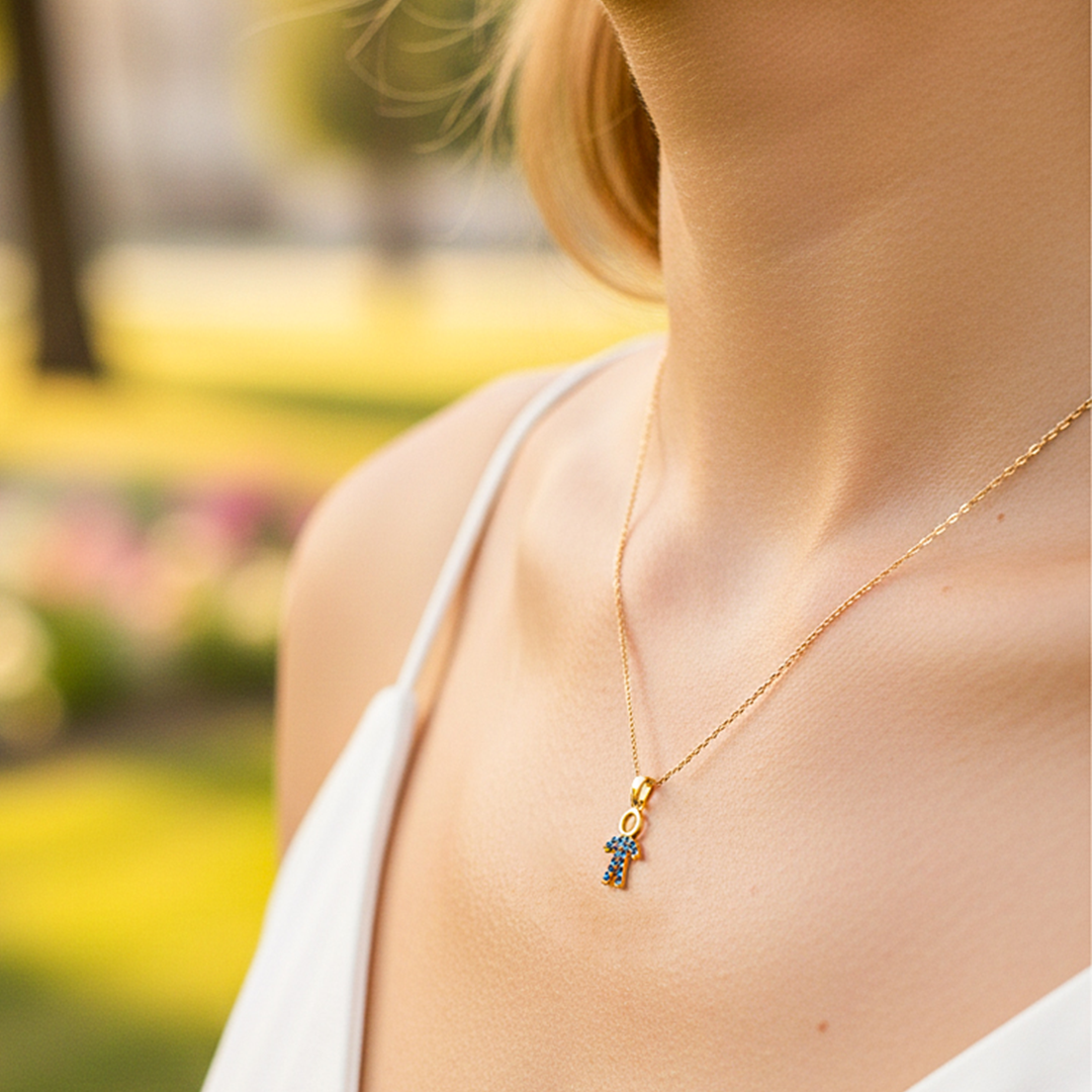 Cuello de modelo usando una cadena con un dije en forma de papá en oro amarillo de 18 quilates con cristales azules de Joyería Caracas.