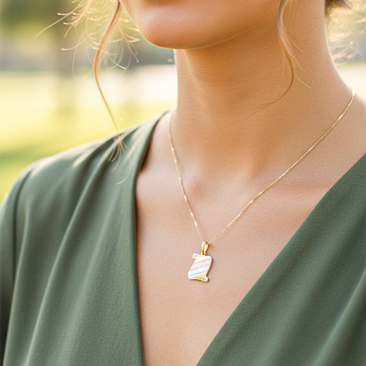 Cuello de modelo usando una cadena con un dije en forma de pergamino en oro amarillo, blanco y rosa de 18 quilates de Joyería Caracas.