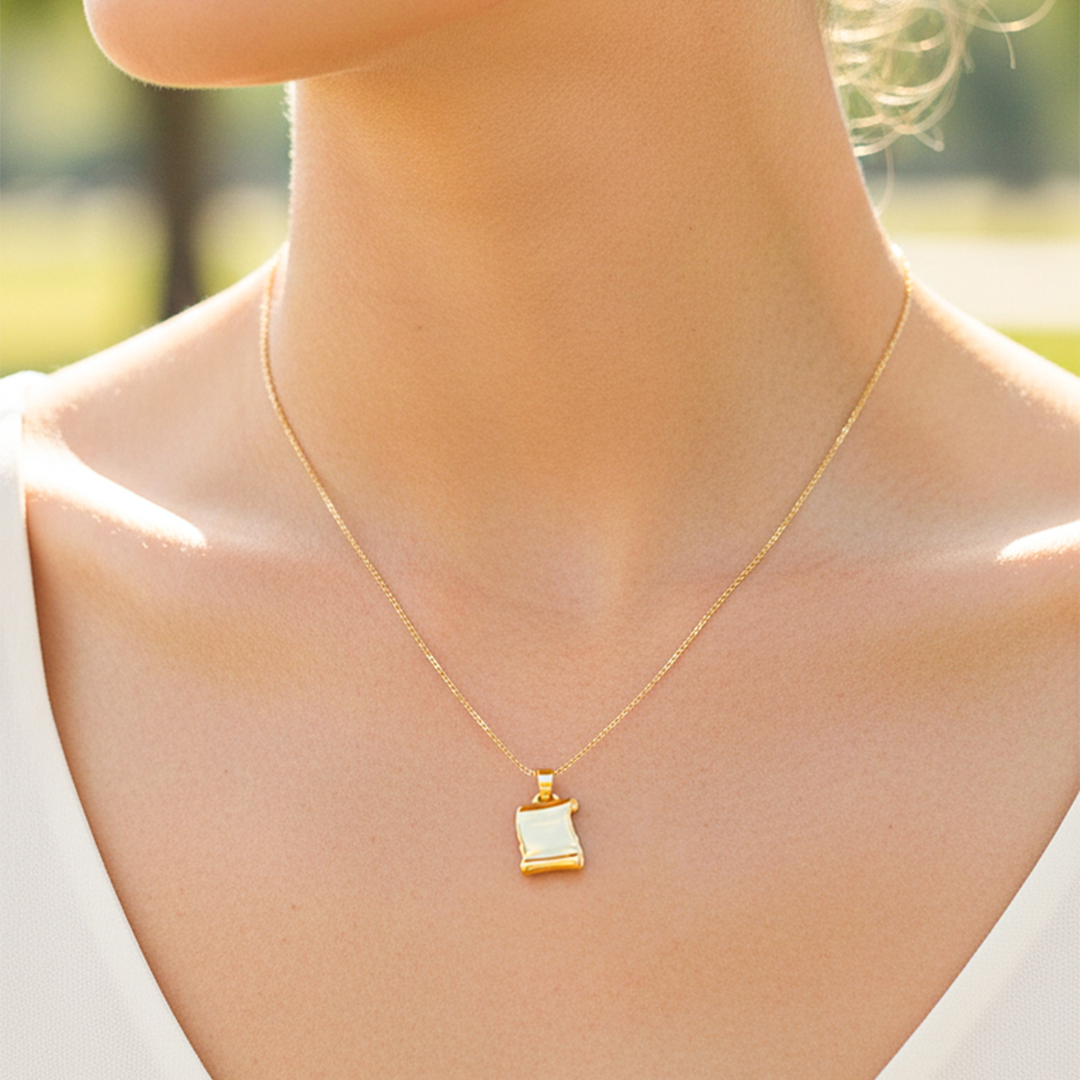 Cuello de modelo usando una cadena con un dije en forma de pergamino en oro amarillo de 18 quilates de Joyería Caracas.