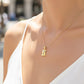 Cuello de modelo usando una cadena con un dije en forma de pergamino con Cristo en oro amarillo y blanco de 18 quilates de Joyería Caracas.