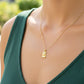 Cuello de modelo usando una cadena con un dije en forma de pergamino con Cristo en oro amarillo y blanco de 18 quilates de Joyería Caracas.