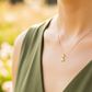 Cuello de modelo usando una cadena con un dije en forma de pies descalzos en oro amarillo de 18 quilates con cristal de Joyería Caracas.
