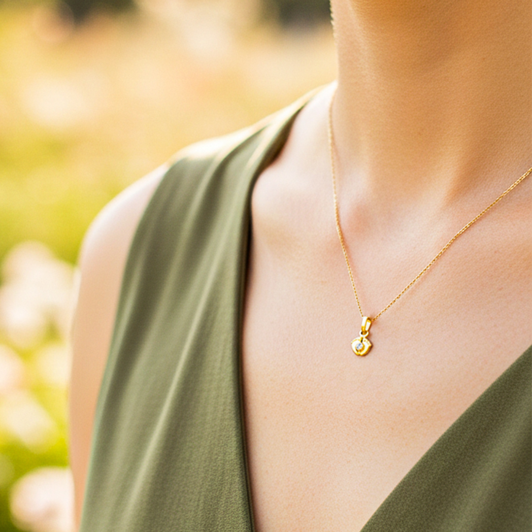 Cuello de modelo usando una cadena con un dije en forma de pies descalzos en oro amarillo de 18 quilates con cristal de Joyería Caracas.