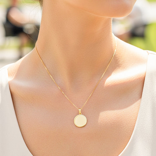 Cuello de modelo usando una cadena con un dije de placa redonda personalizable en oro amarillo de 18 quilates de Joyería Caracas.