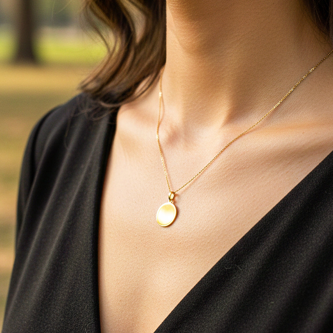 Cuello de modelo usando una cadena con un dije en forma de placa redonda para personalizar en oro amarillo de 18 quilates de Joyería Caracas.