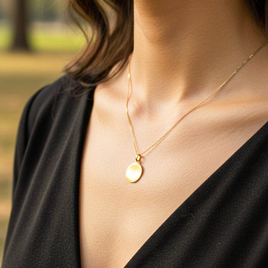 Cuello de modelo usando una cadena con un dije en forma de placa redonda para personalizar en oro amarillo de 18 quilates de Joyería Caracas.