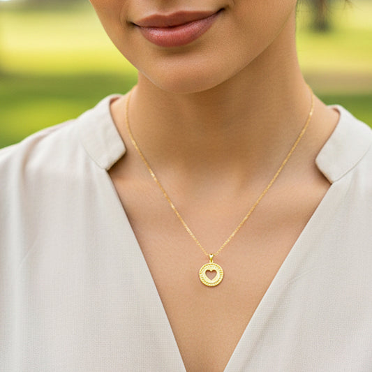 Cuello de modelo usando una cadena con un dije redondo con la silueta de un corazón en oro amarillo de 18 quilates de Joyería Caracas.