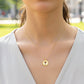 Cuello de modelo usando una cadena con un dije redondo con la silueta de una cruz en oro amarillo de 18 quilates de Joyería Caracas.