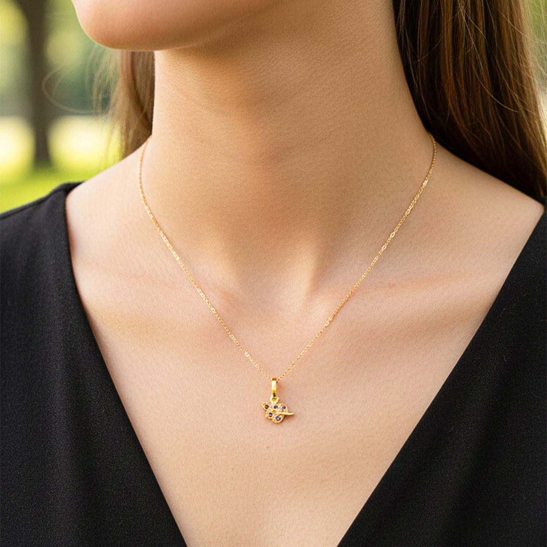 Cuello de modelo usando una cadena con un dije en forma de racimo en oro amarillo de 18 quilates con cristales rojos de Joyería Caracas.