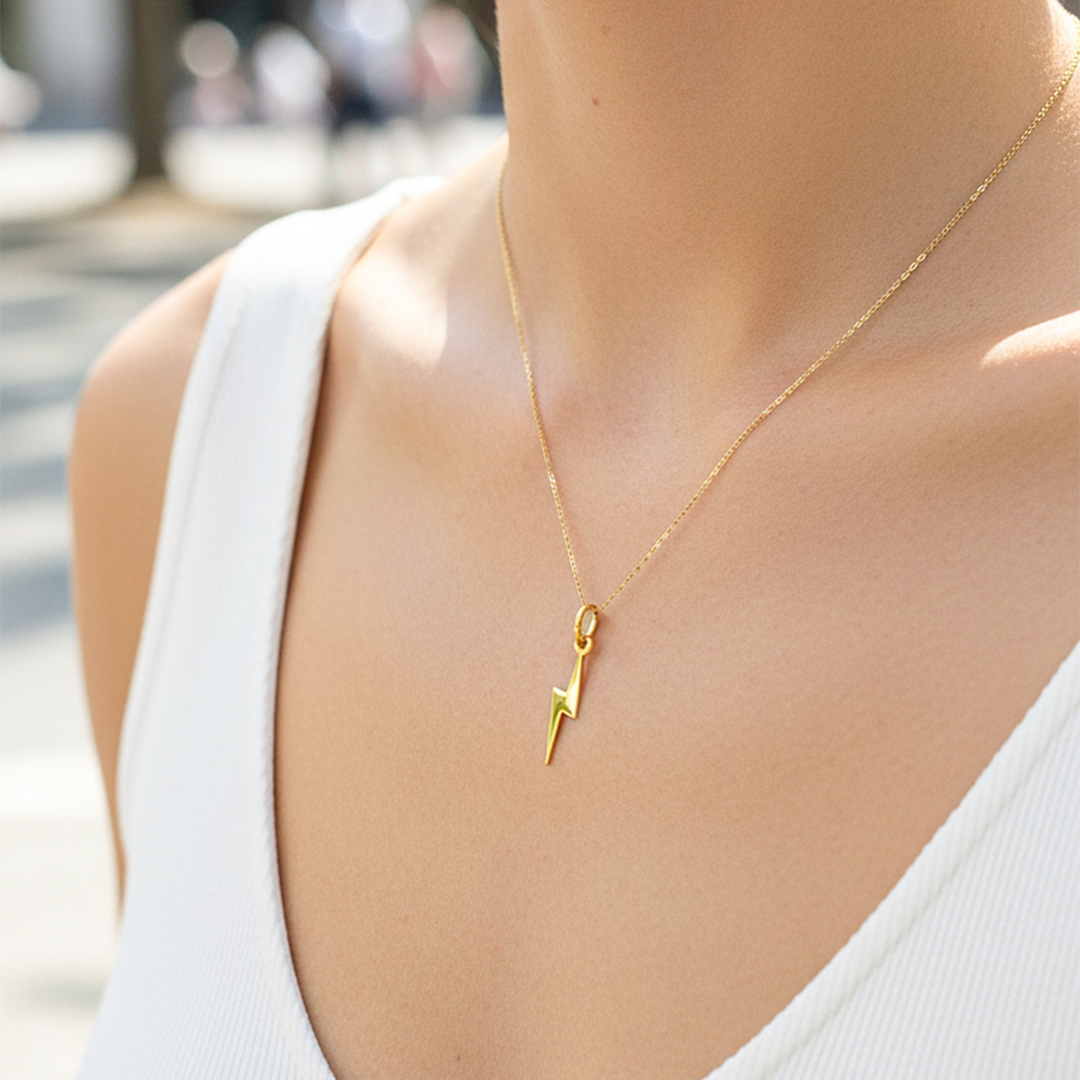 Cuello de modelo usando una cadena con un dije en forma de rayo liso en oro amarillo de 18 quilates de Joyería Caracas.