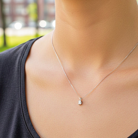 Cuello de modelo usando una cadena con un dije en forma rectangular en oro blanco de 18 quilates con cristal de Joyería Caracas.