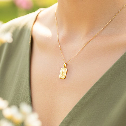 Cuello de modelo usando una cadena con un dije en forma de placa grabada con el rostro de la Virgen de Guadalupe en oro amarillo de 18 quilates de Joyería Caracas.