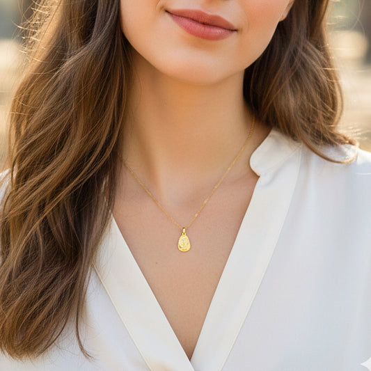 Cuello de modelo usando una cadena con un dije de placa en forma de pera con el rostro de la Virgen en oro amarillo de 18 quilates de Joyería Caracas.