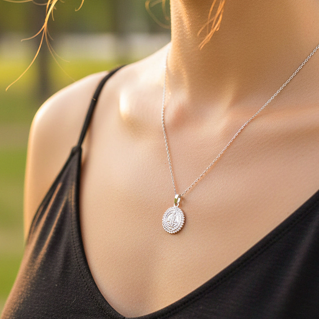 Cuello de modelo usando una cadena con un dije de San Benito oro blanco de 18 quilates con cristales de Joyería Caracas.