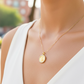 Cuello de modelo usando una cadena con un dije en forma de San Benito en oro amarillo de 18 quilates con cristales de Joyería Caracas.