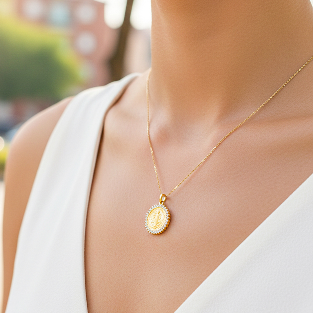 Cuello de modelo usando una cadena con un dije en forma de San Benito en oro amarillo de 18 quilates con cristales de Joyería Caracas.