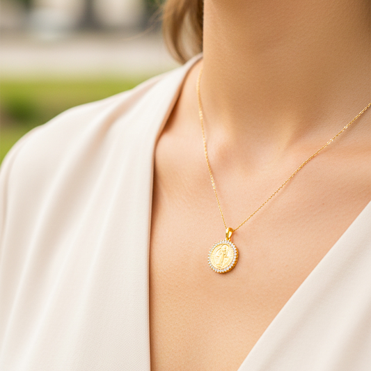 Cuello de modelo usando una cadena con un dije en forma de San Benito en oro amarillo de 18 quilates con cristales de Joyería Caracas.