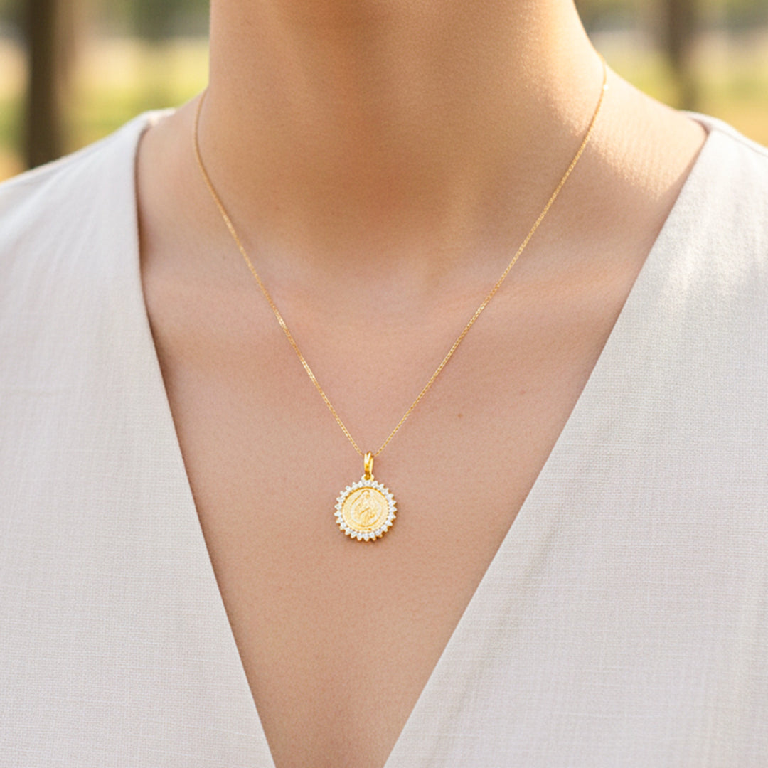 Cuello de modelo usando una cadena con un dije en forma de San Benito en oro amarillo de 18 quilates con cristales de Joyería Caracas.