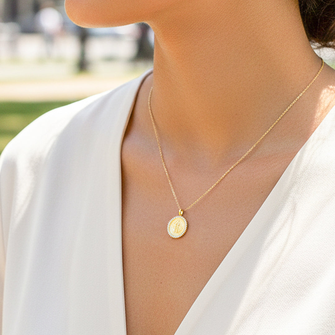 Cuello de modelo usando una cadena con un dije en forma de San Benito en oro amarillo de 18 quilates con cristales de Joyería Caracas.