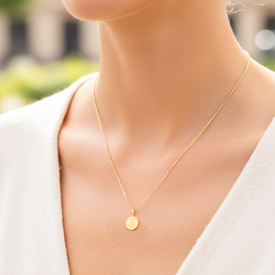 Cuello de modelo usando una cadena con un dije en forma de San Benito en oro amarillo de 18 quilates de Joyería Caracas.