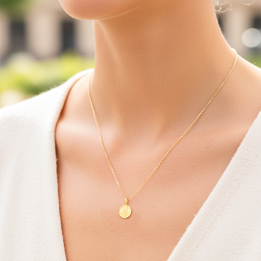 Cuello de modelo usando una cadena con un dije en forma de San Benito en oro amarillo de 18 quilates de Joyería Caracas.