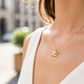 Cuello de modelo usando una cadena con un dije en forma de sobre de carta en oro amarillo de 18 quilates de Joyería Caracas.