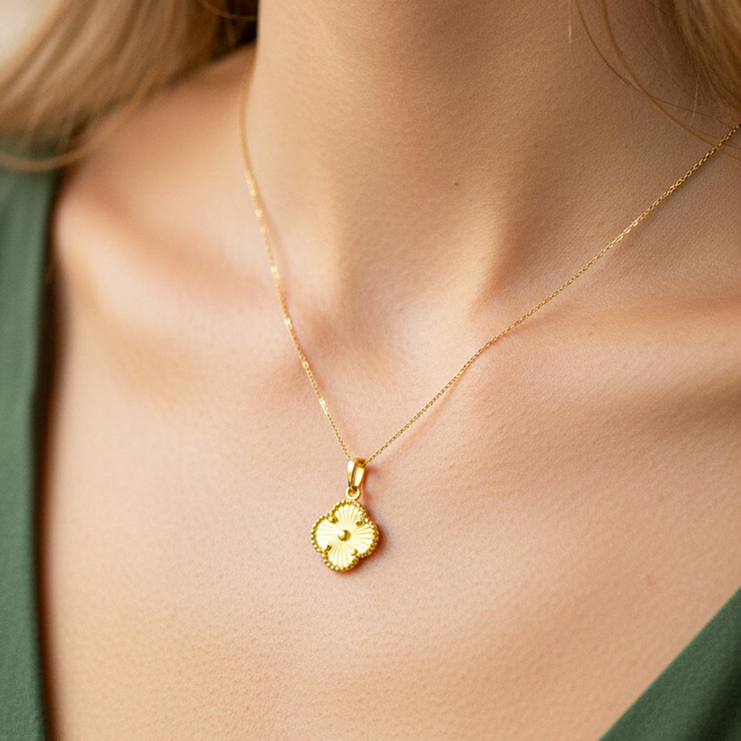 Cuello de modelo usando una cadena con un dije en forma de trébol diamantado en oro amarillo de 18 quilates de Joyería Caracas.