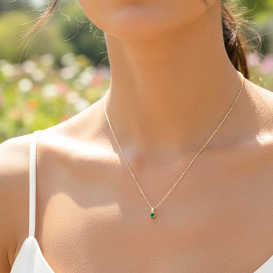 Cuello de modelo usando una cadena con un dije ovalado en oro amarillo de 18 quilates y Esmeralda de Joyería Caracas.