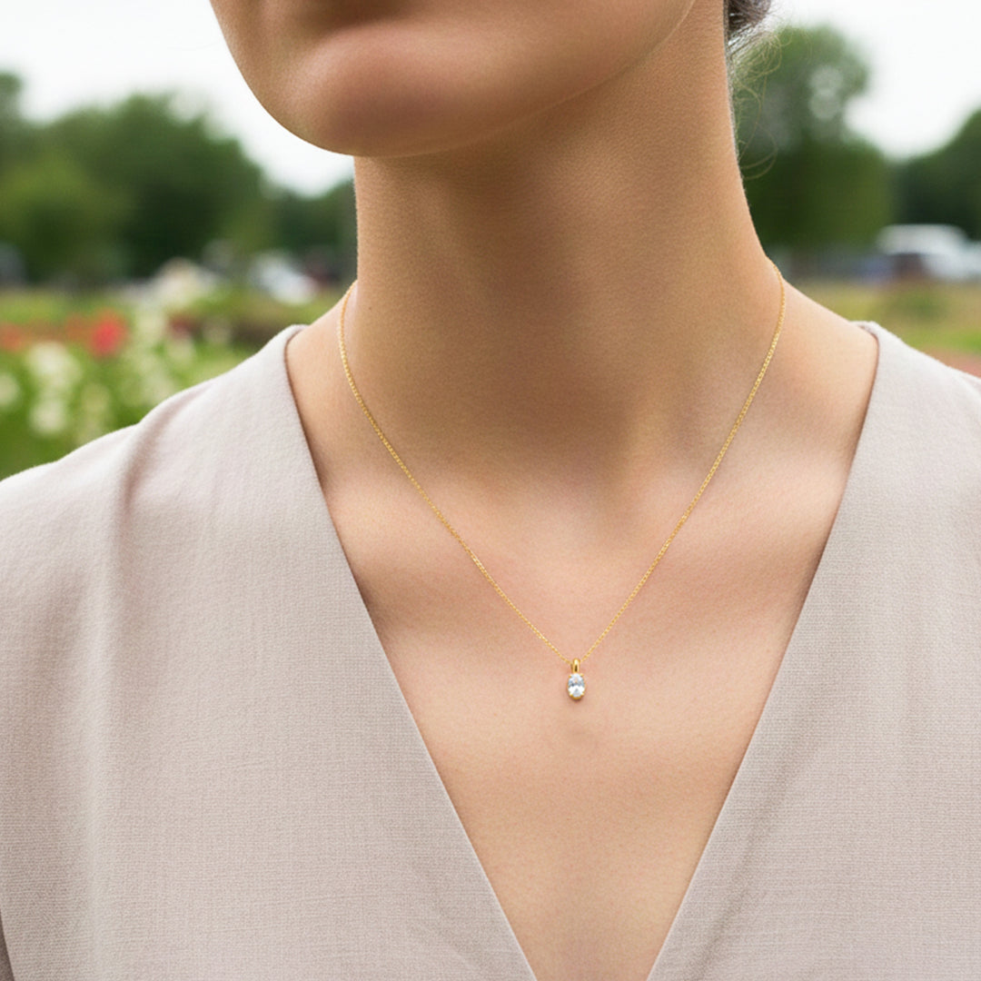 Cuello de modelo usando una cadena con un dije en forma de corazón en oro amarillo de 18 quilates con cristal ovalado de Joyería Caracas.