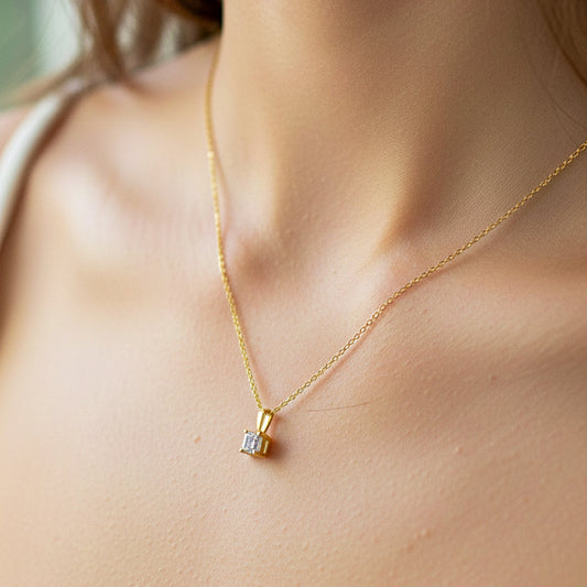 Cuello de modelo usando una cadena con un dije en oro amarillo de 18 quilates con cristal en corte cuadrado de Joyería Caracas.