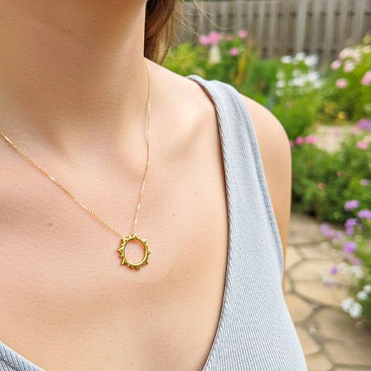 Cuello de modelo usando una cadena con un dije en forma de sol pasante en oro amarillo de 18 quilates de Joyería Caracas.