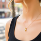 Cuello de modelo usando una cadena con un dije en forma de osito Teddy en oro amarillo de 18 quilates de Joyería Caracas.